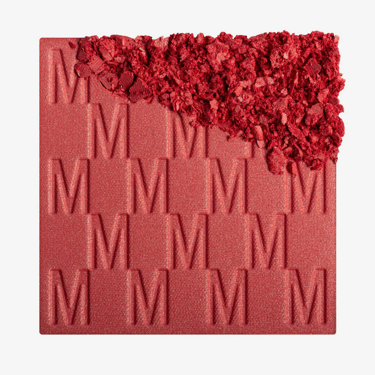 Das Rouge At First Blush von Mesauda Beauty mit eingeprägtem M-Muster, die obere, rechte Ecke ist in losem Puder zerkleinert dargestellt.
