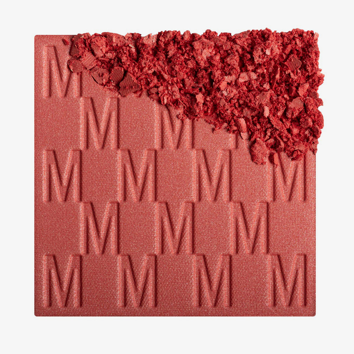 Das Rouge At First Blush von Mesauda Beauty mit eingeprägtem M-Muster, die obere, rechte Ecke ist in losem Puder zerkleinert dargestellt.

