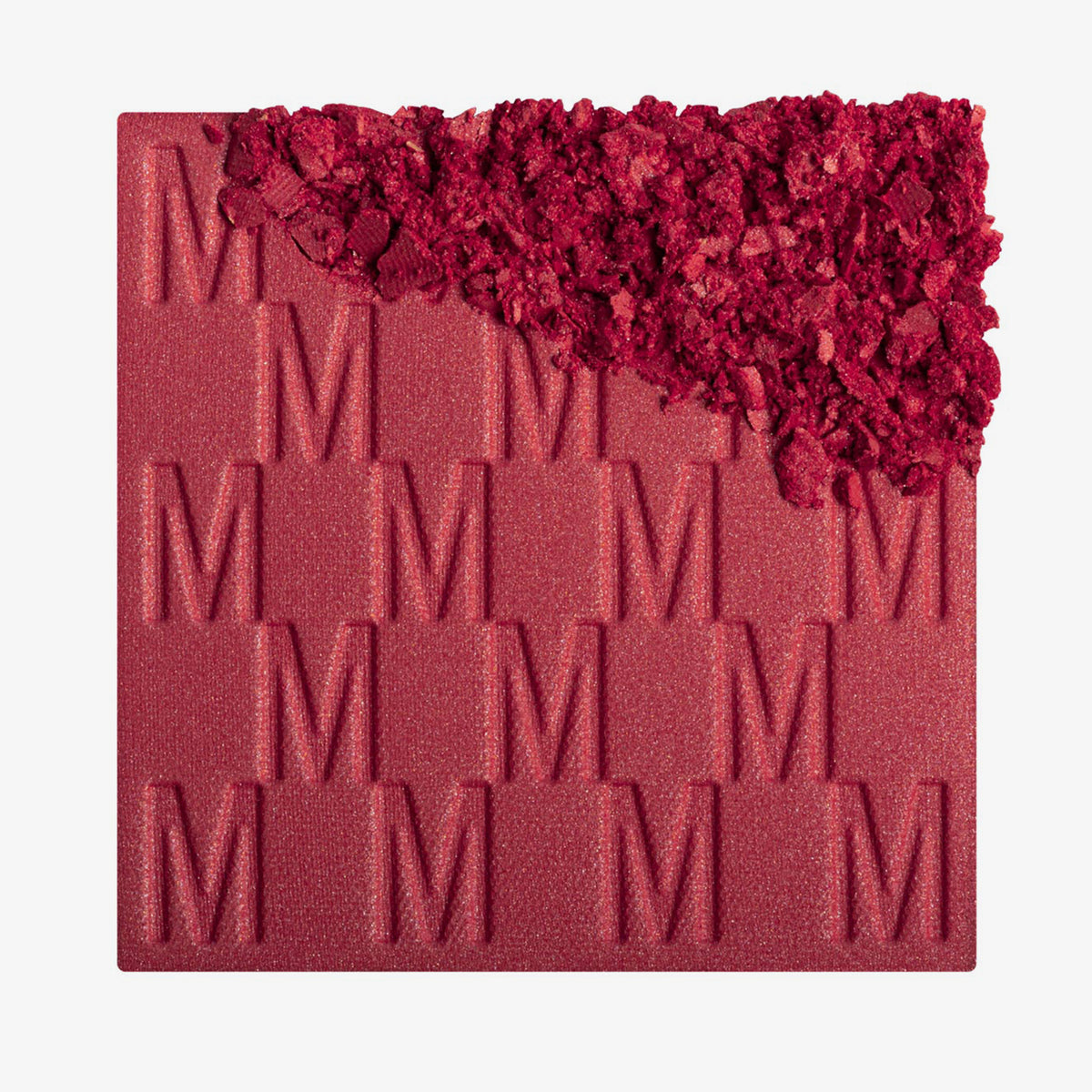 Das Rouge At First Blush von Mesauda Beauty mit eingeprägtem M-Muster, die obere, rechte Ecke ist in losem Puder zerkleinert dargestellt.
