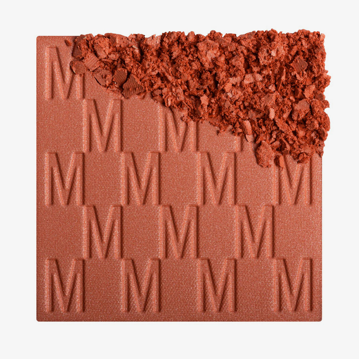 Das Rouge At First Blush von Mesauda Beauty mit eingeprägtem M-Muster, die obere, rechte Ecke ist in losem Puder zerkleinert dargestellt.
