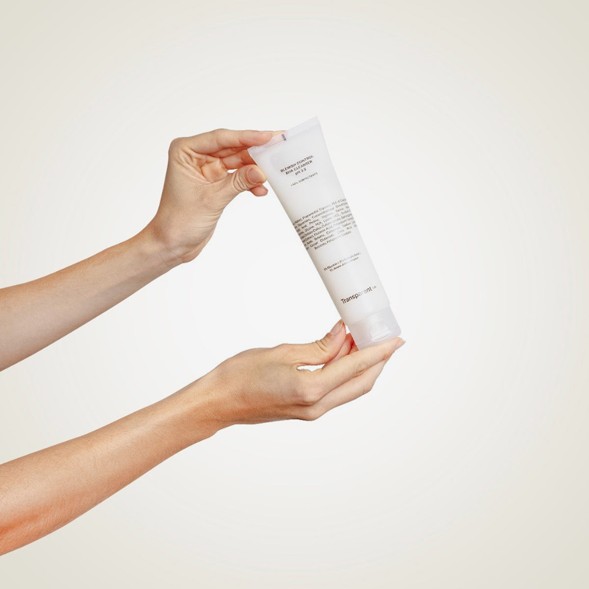 Hände halten die Tube Blemish Control BHA Cleanser vor einem hellen Hintergrund.