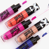 Fünf leuchtende Stacey Marie x BPerfect CARNIVAL 3 Lipgloss-Tuben in Lila-, Orange-, Pink-, Beige- und Blautönen auf weißem Hintergrund.
