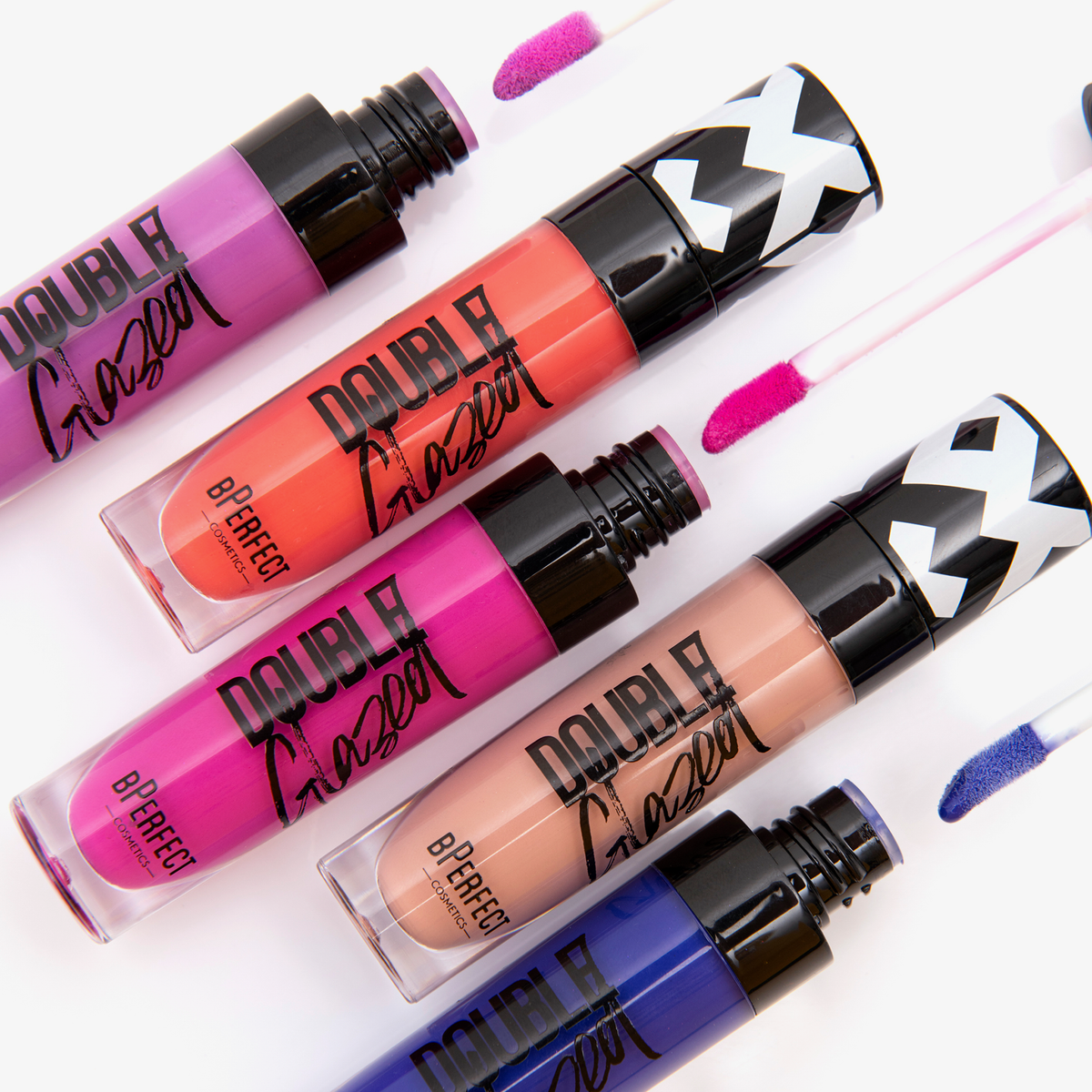 Fünf leuchtende Stacey Marie x BPerfect CARNIVAL 3 Lipgloss-Tuben in Lila-, Orange-, Pink-, Beige- und Blautönen auf weißem Hintergrund.