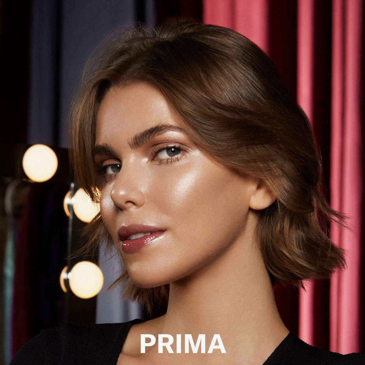 Eine Frau trägt den Mesauda Beauty Nude Venus Puder und blickt in die Kamera, hinter ihr sind drei Leuchtpunkte. Unten steht: PRIMA