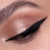 Nahaufnahme eines Auges mit schimmerndem rosa Lidschatten und einem kräftigen schwarzen Eyeliner, der mit dem wasserfesten Bombay Black Eye Pencil gezeichnet wurde.