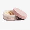 Offenes Glas Smooth & Blur Setting Powder mit rosa Deckel und der Aufschrift DOMINIQUE vor weißem Hintergrund.