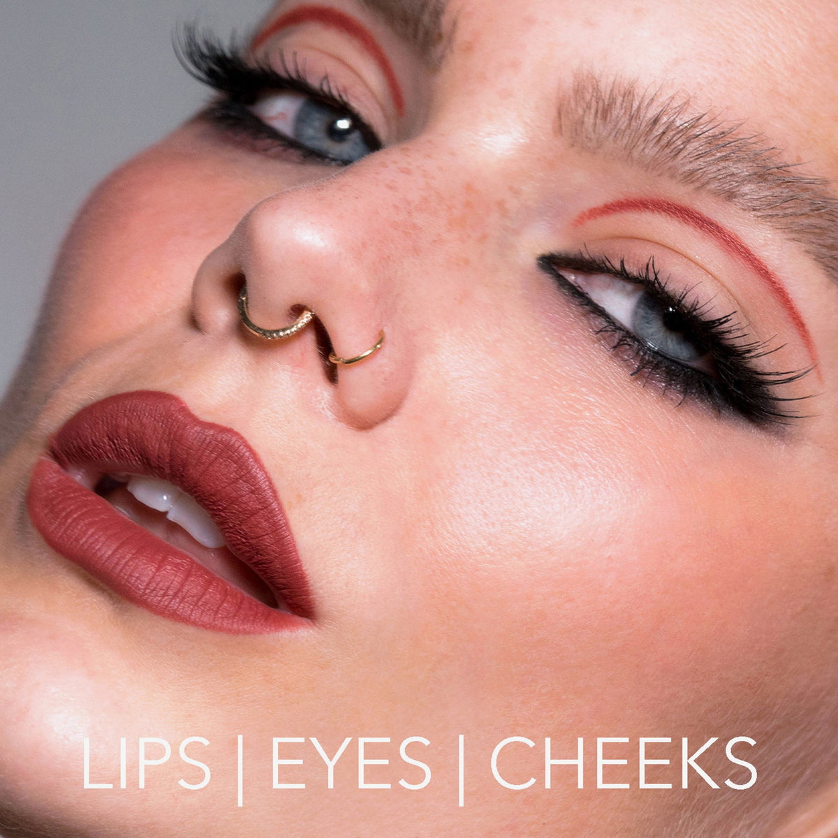 Nahaufnahme einer Frau mit auffälligem Make-up, Lidstrich und roten Lippen, kreiert mit dem Crayon Lipliner Cherry von LH Cosmetics. Text: Lips | Eyes | Cheeks.