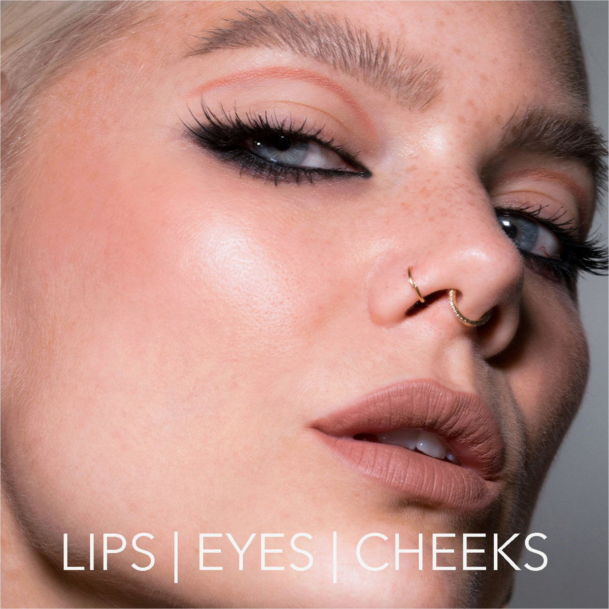 Nahaufnahme einer Frau mit auffälligem Make-up, Lidstrich und nudefarbenen Lippen, kreiert mit dem Crayon Lipliner Rosy Nougat von LH Cosmetics. Text: Lips | Eyes | Cheeks.