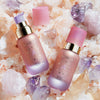 Zwei rosa getönte NABLA Angel Aura-Flaschen mit sichtbaren Deckeln und Pumpen auf rosa und violetten Kristallen und Salz.