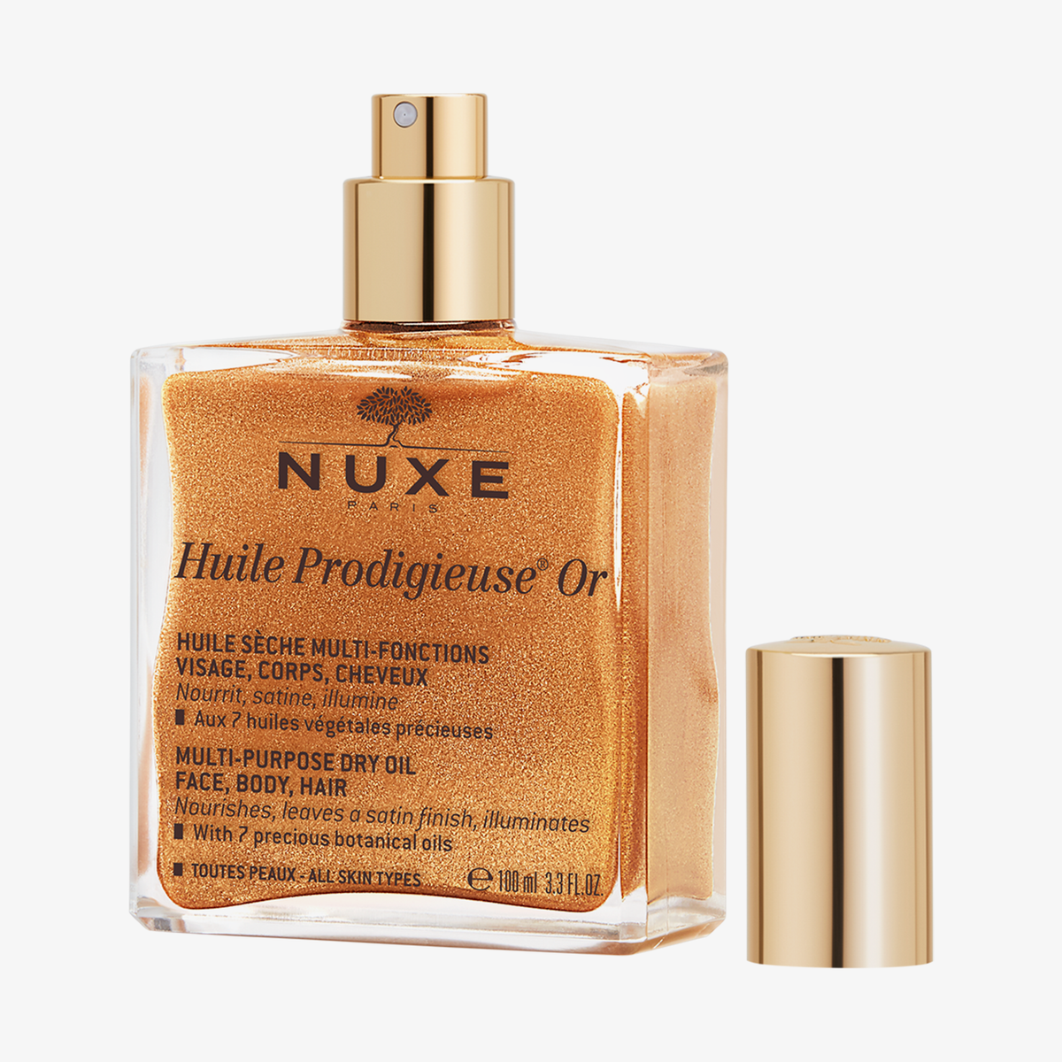 Eine geöffnete Flasche NUXE Huile Prodigieuse® OR mit goldenem Schimmer und Sprühverschluss mit der goldenen Kappe daneben.