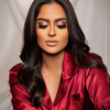 Frau mit langem dunklem Haar, in einem roten Satintop und geschlossenen Augen, präsentiert glamouröses Make-up, das mit der Unconditional Palette kreiert wurde.