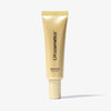 Eine gold-gelbe Tube LH Cosmetics Shaping Light Warm Glow steht vor einem weißen Hintergrund.