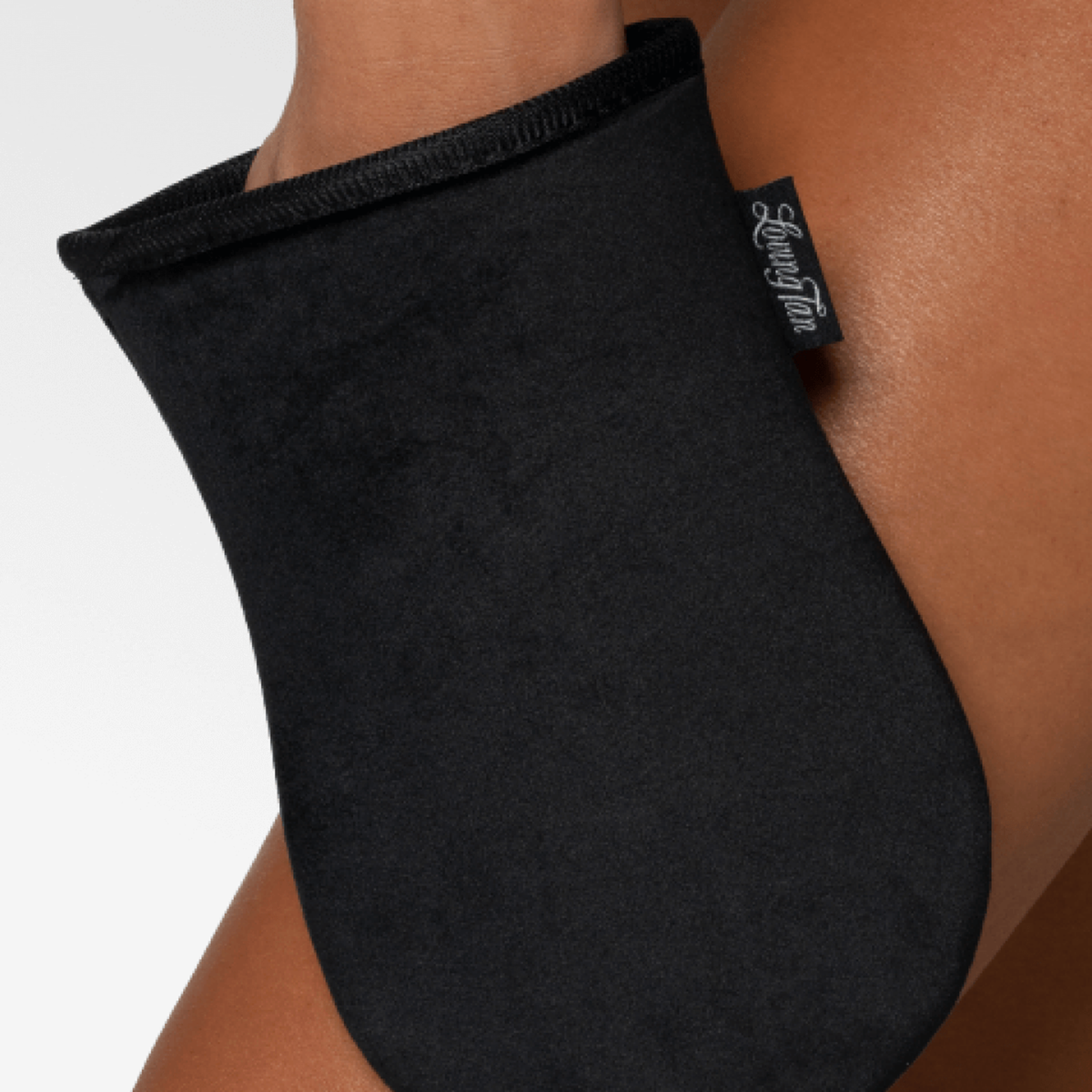 Schwarzer Selbstbräuner-Handschuh von Loving Tan auf gebräunter Haut.