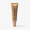 Eine bronze-goldene Tube LH Cosmetics Shaping Light Desert Glow steht vor einem weißen Hintergrund.