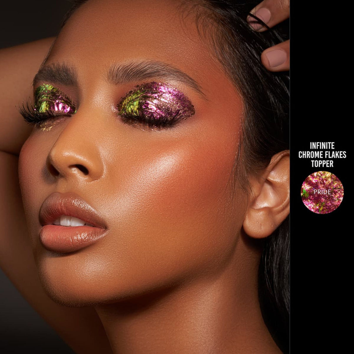 Person mit geschlossenen Augen und mittlerem Hautton präsentiert schimmernden, irisierenden Make-up-Look mit den Infinite Chrome Flakes Pride.