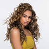 Frau mit langen glänzenden, definierten Locken präsentiert Wirkung des Dream Coat For Curly Hair vor einem hellen Hintergrund.