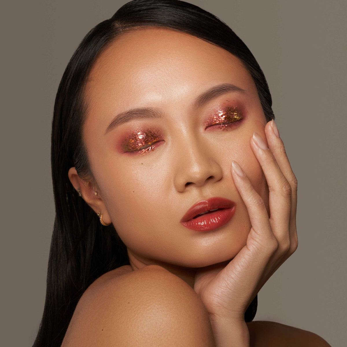 Person mit geschlossenen Augen und hellem Hautton präsentiert schimmernden, irisierenden Make-up-Look mit den Infinite Chrome Flakes Hot Lava.